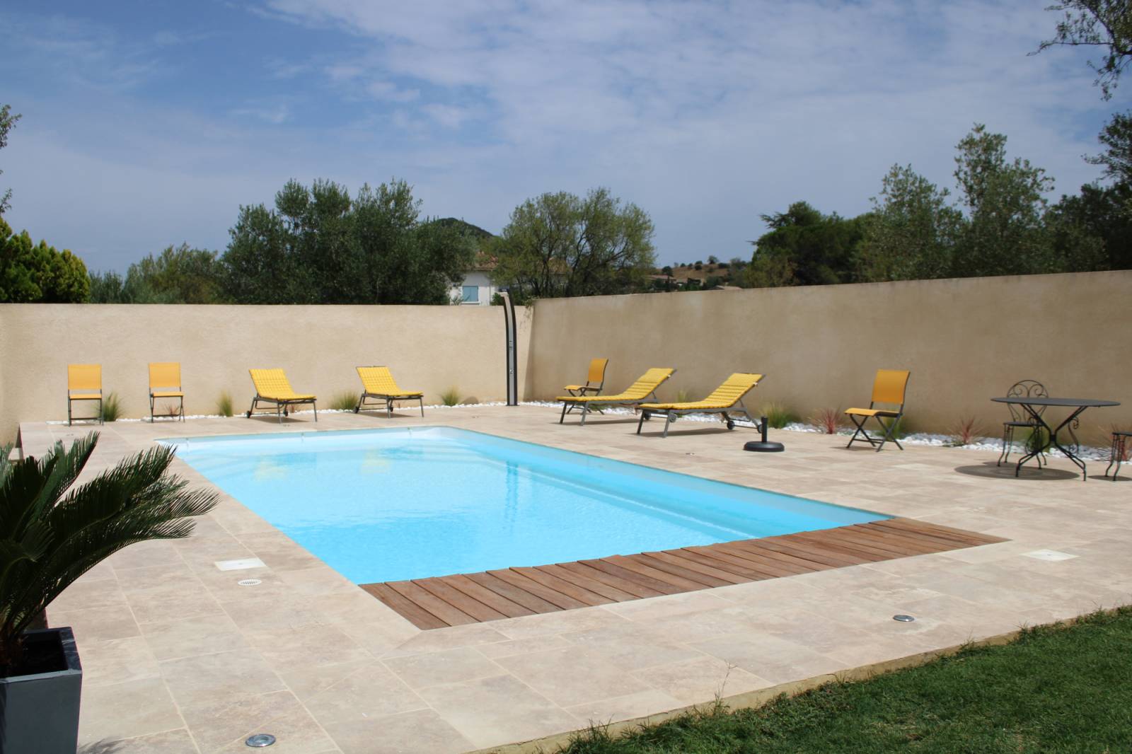 Réalisation d'une piscine coque modèle MANAE à Saint BONNET DU GARD à coté de REMOULINS, avec volet immergé , margelles en travertin beige 3 cm bord rond.