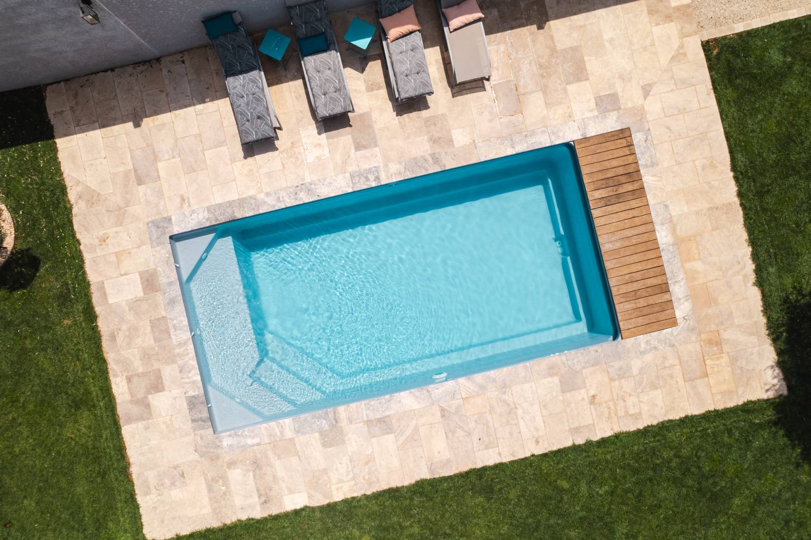 MOTU : Piscine coque polyester avec volet immergé, un escalier d'angle et une plage