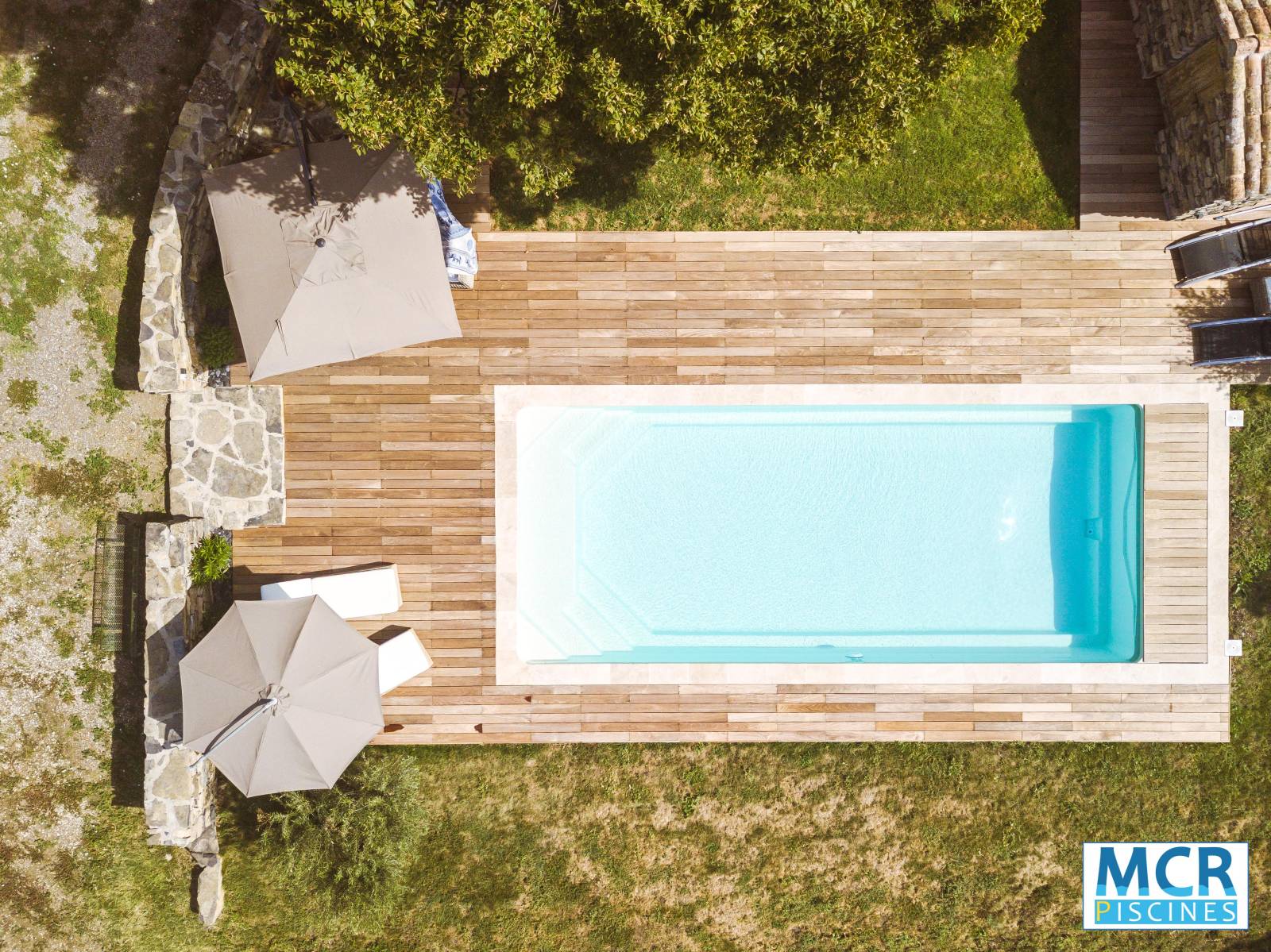 MATAURA : Piscine coque polyester avec couverture automatique immergée, deux escaliers d'angles et une plage au centre