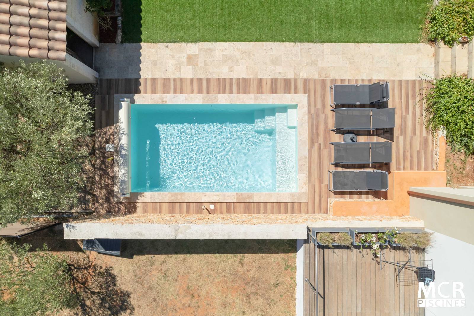 MAKENA : Piscine coque polyester avec un escalier d'angle et une grande plage