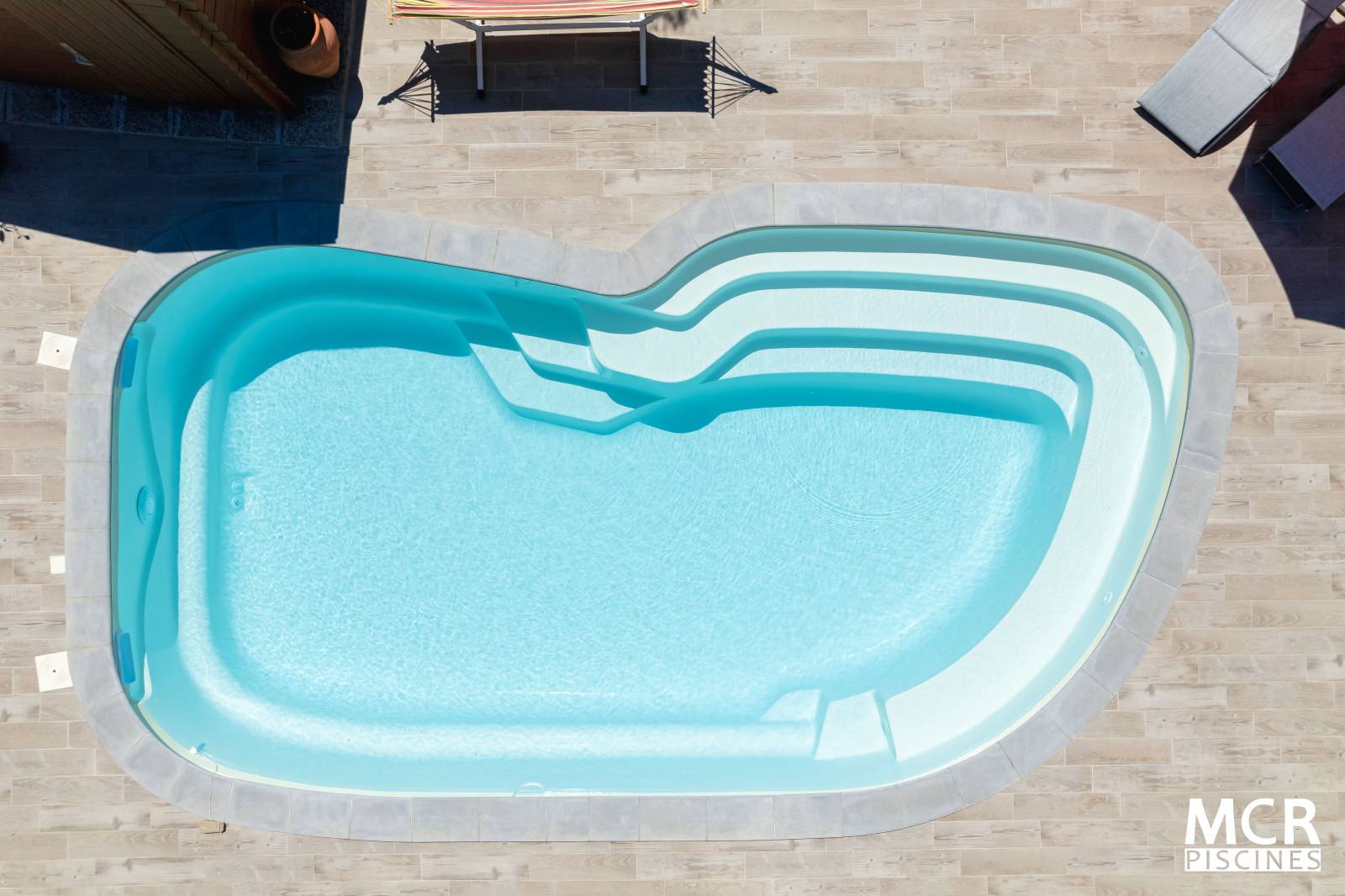 UVEA : Piscine coque polyester de forme ovale avec un large escalier arrondie