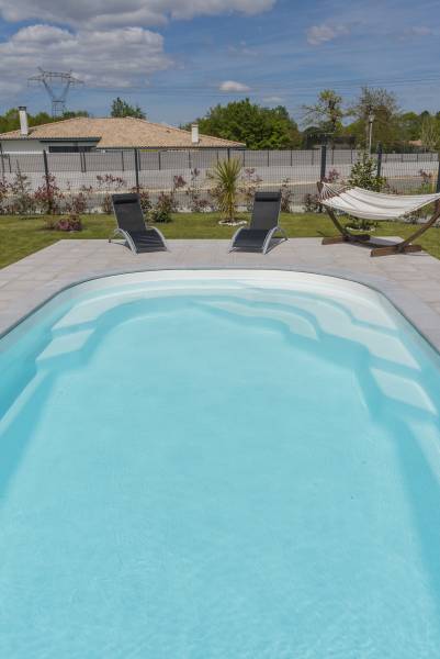 MAUI : Piscine coque polyester en fond incliné avec escalier d'angle et une banquette