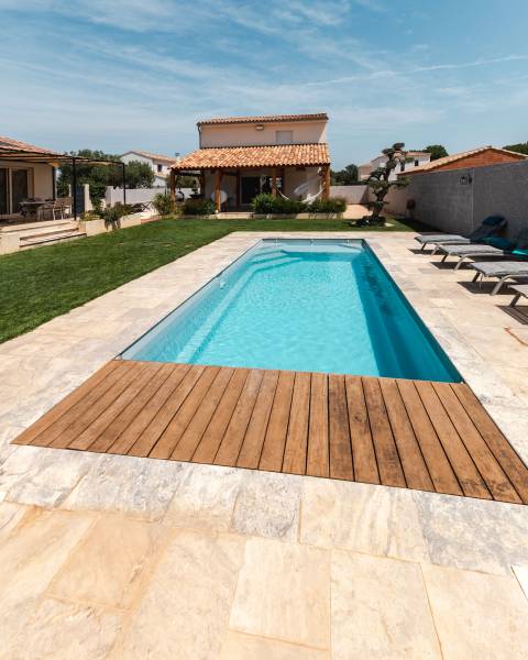 MOTU : Piscine coque polyester avec volet immergé, un escalier d'angle et une plage