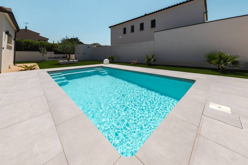 Installation d'une piscine coque à Poulx à proximité de Marguerittes, modèle BAHAMAS de couleur gris clair.