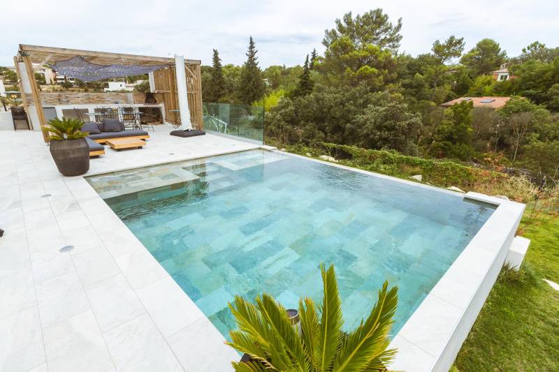 Piscine traditionnelle avec débordement et revêtement en carrelage de Bali