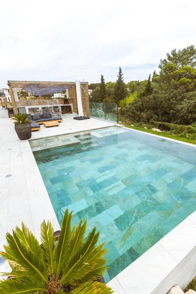 Piscine traditionnelle avec débordement et revêtement en carrelage de Bali