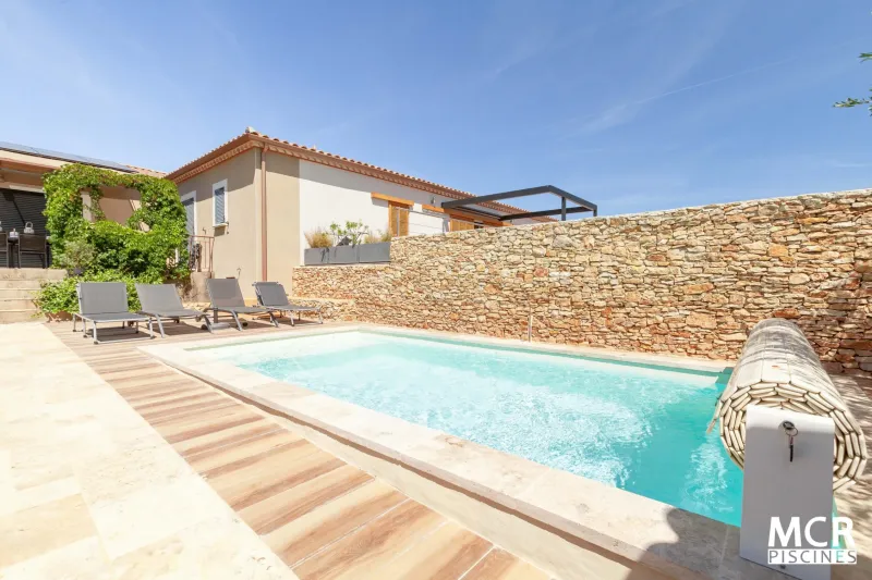 Réalisation d'une pose de piscine coque polyester modèle Makena à Poulx près de Nîmes, avec couverture automatique hors sol.