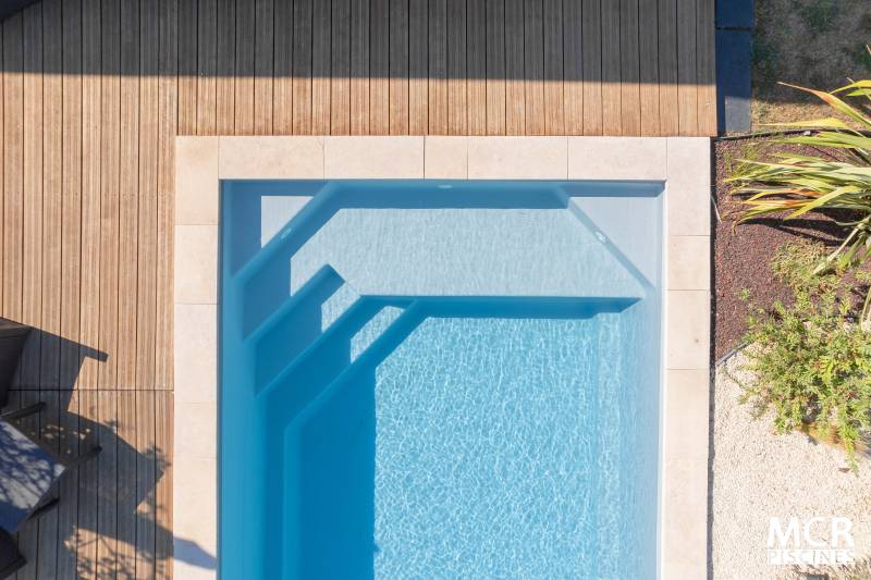 MANURÉVA : Piscine coque polyester avec une banquette et un escalier d'angle