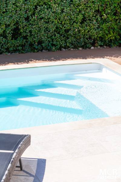 MOTU : Piscine coque polyester avec volet immergé, un escalier d'angle et une plage