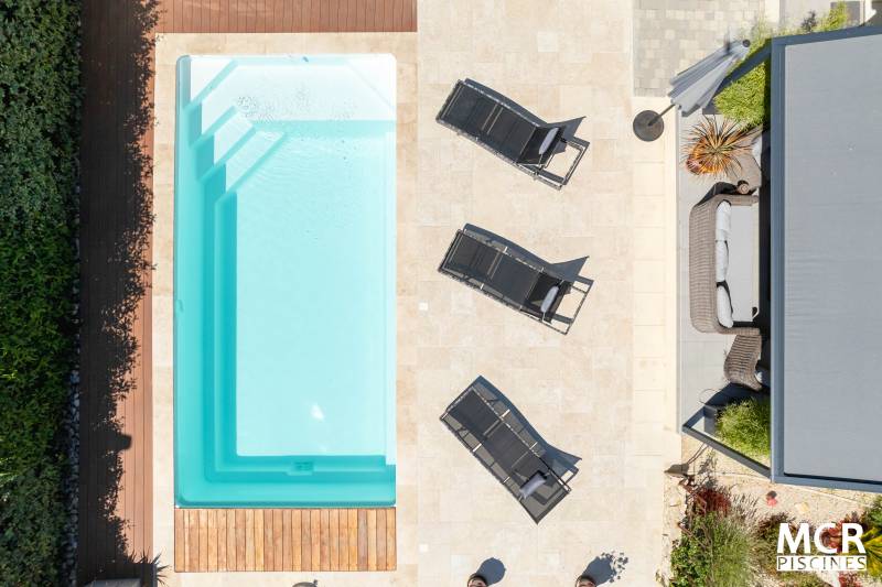 MOTU : Piscine coque polyester avec volet immergé, un escalier d'angle et une plage