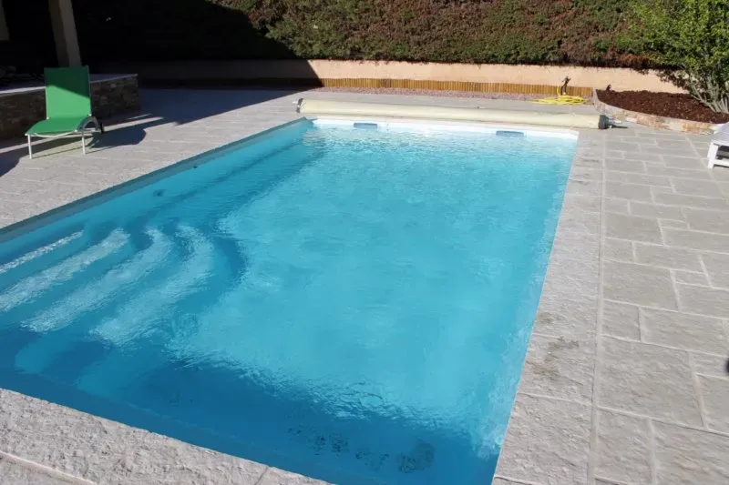 Vue de la piscine à coque Bornéo en coloris bleu, modèle avec fond plat et banquette intégrée