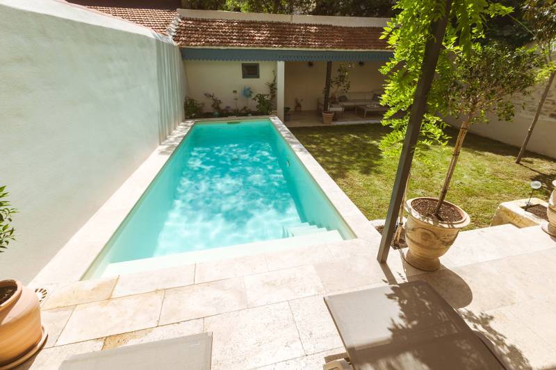 Piscine traditionnelle avec revêtement en membrane armée de couleur sable et margelles en travertins beige